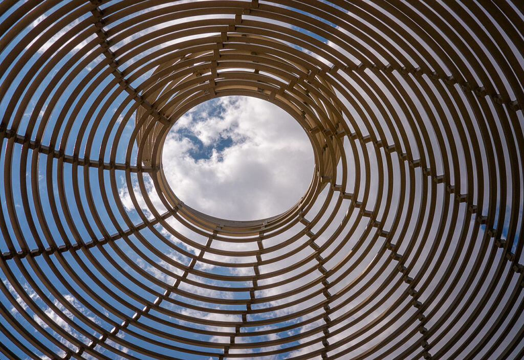 Durch eine geflochtene Spirale ist ein Wolkenhimmel zu sehen