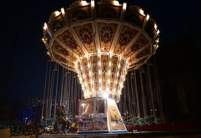 Ein Kettenkarussel auf dem Weihnachtsmarkt leuchtet schön in der Dunkelheit