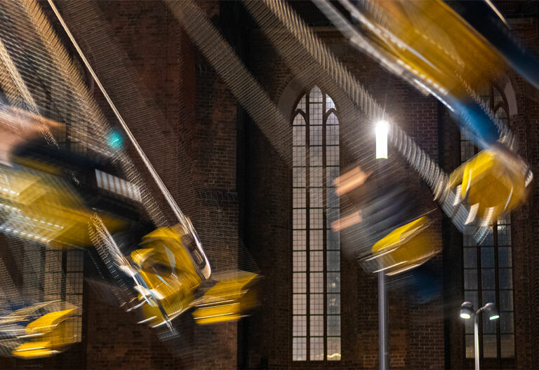 Ein Kettenkarussel dreht sich dynamisch vor der Marienkirche